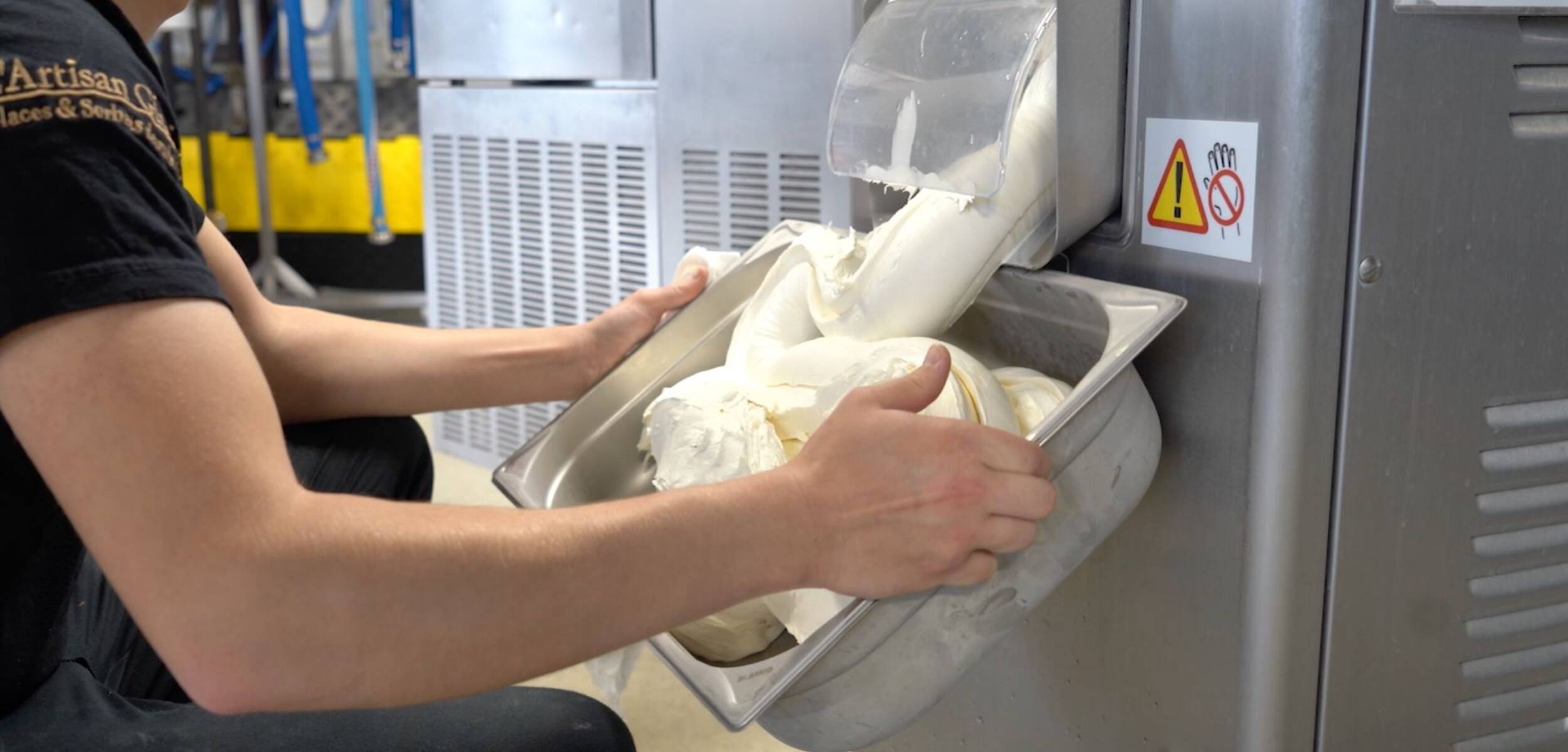 Une personne qui récolte dans un bac de la masse alimentaire produite par une machine